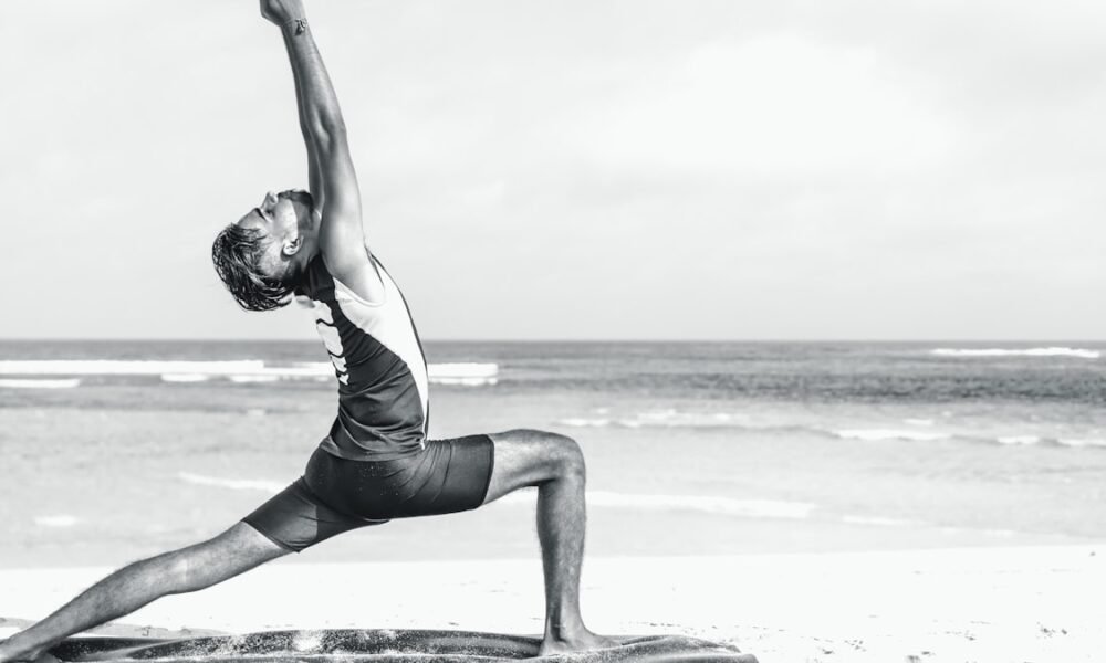 Person stretching in a yoga pose on the seashore at sunrise