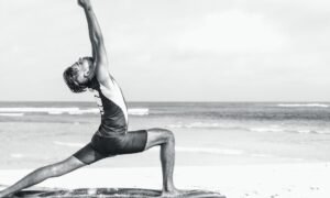 Person stretching in a yoga pose on the seashore at sunrise