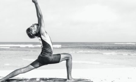 Person stretching in a yoga pose on the seashore at sunrise