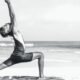 Person stretching in a yoga pose on the seashore at sunrise