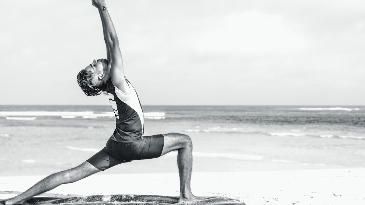 Person stretching in a yoga pose on the seashore at sunrise