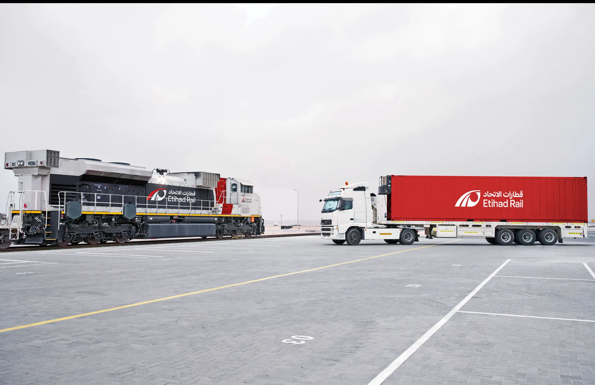 Etihad Rail freight locomotive beside a branded container truck in the UAE